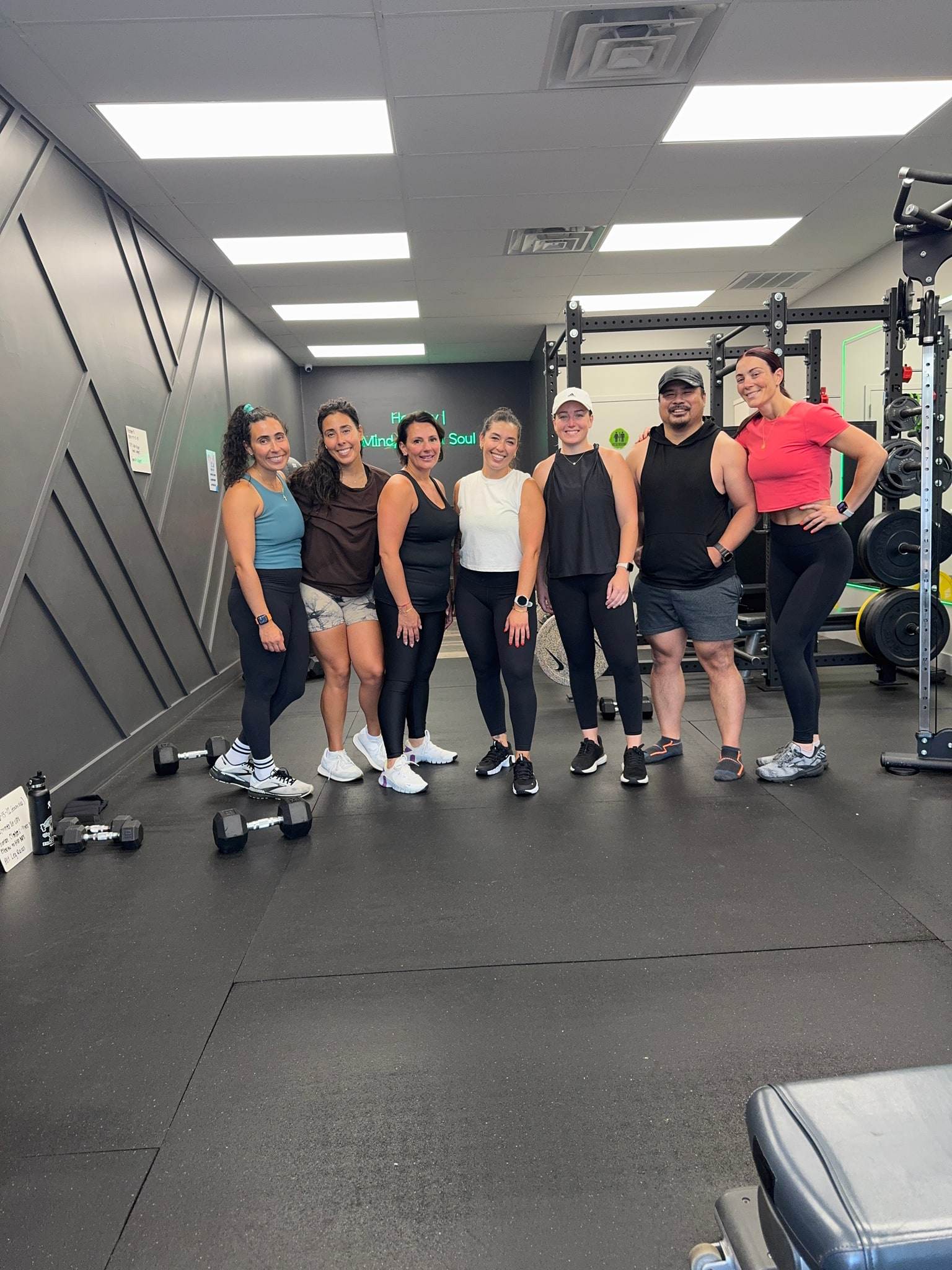 Members of The Balanced Class smiling together on the studio floor at Balanced Health Fitness in Seaford, NY.