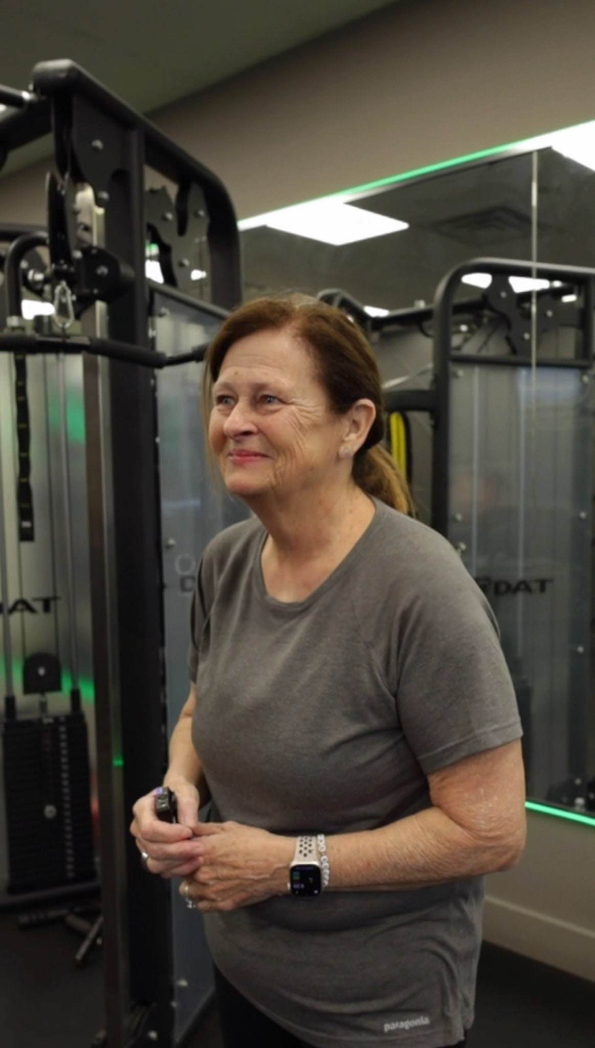 Irene, a super grandma, smiling at the cable machine at Balanced Health Fitness in Seaford, NY.